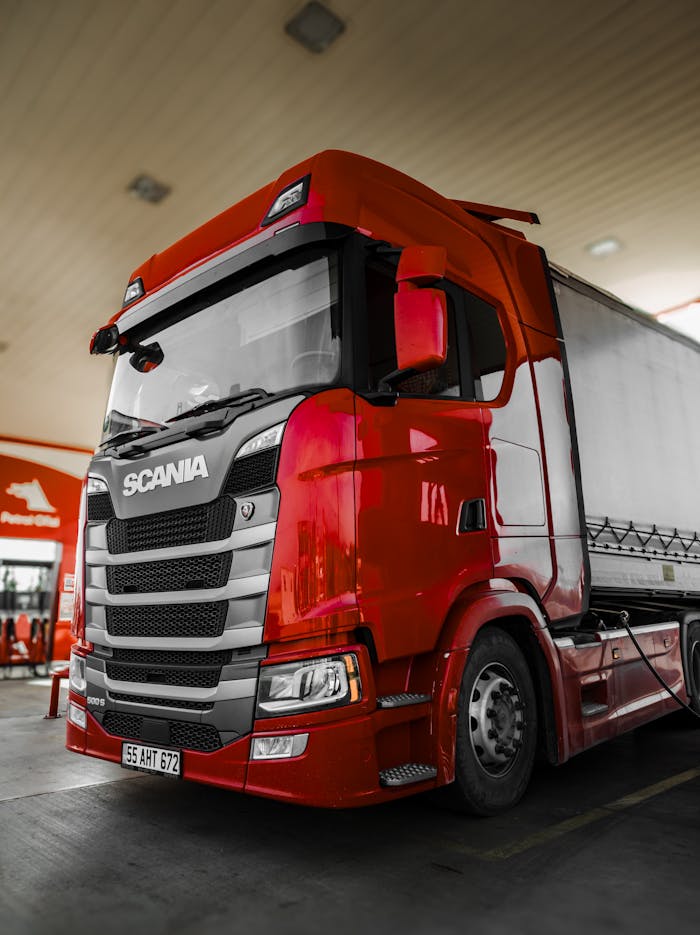 Bright red Scania truck parked at a fuel station with modern design and clean lines.